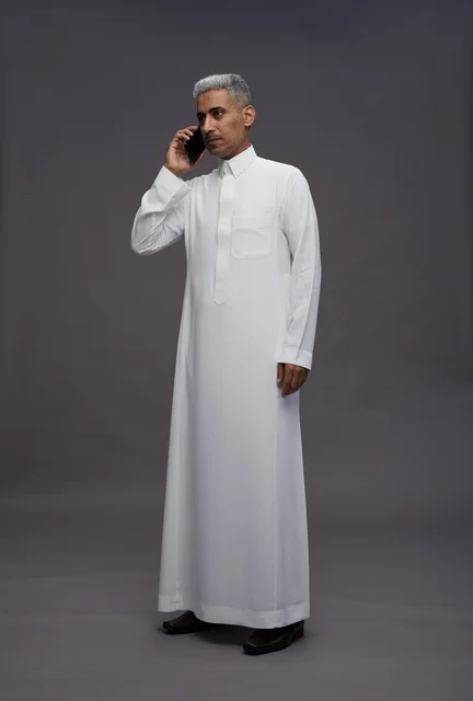 Saudi Man in White Thobe Talking on Smartphone