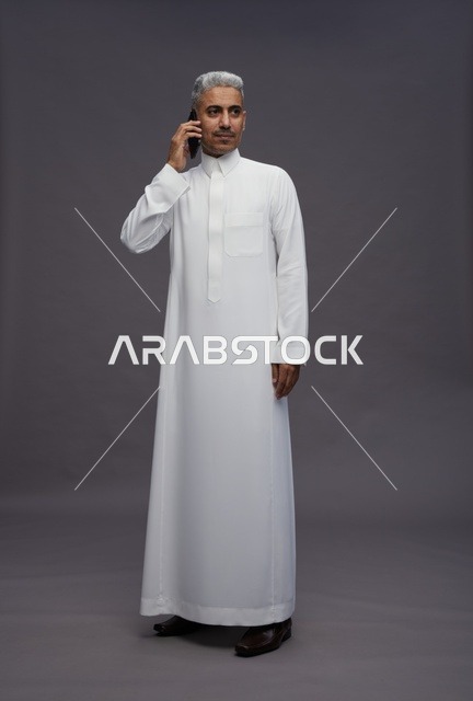 رجل سعودي بالثوب الأبيض يتحدث عبر الهاتف المحمول