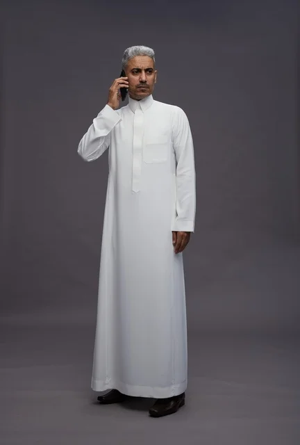 Saudi Man in White Thobe Talking on Smartphone