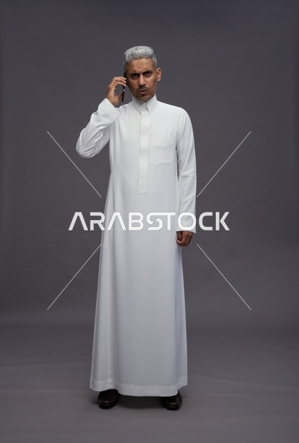 رجل سعودي بالثوب الأبيض يتحدث عبر الهاتف المحمول