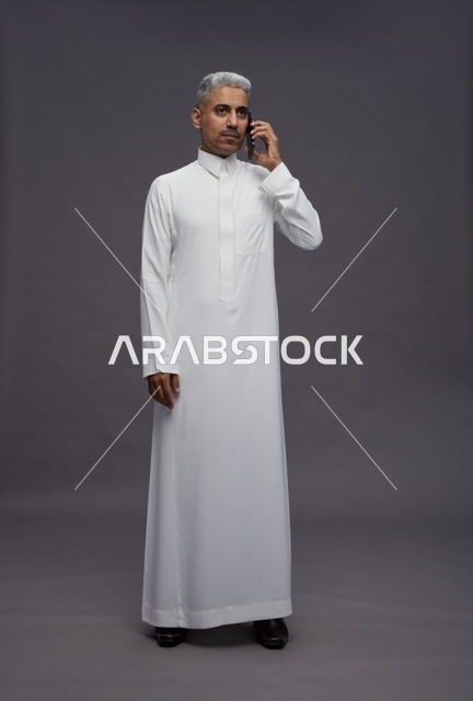 رجل سعودي بالثوب الأبيض يتحدث عبر الجوال