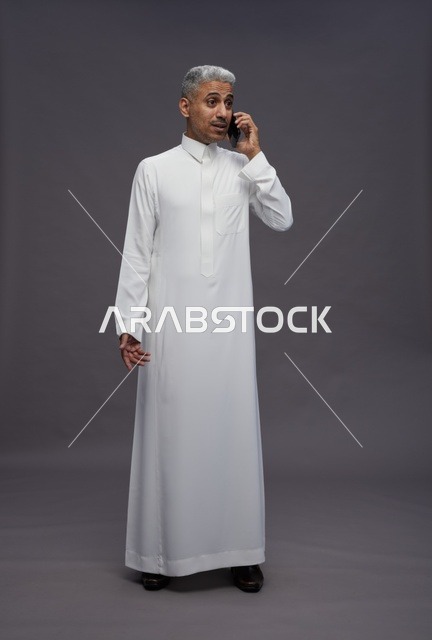 رجل سعودي بالثوب الأبيض يتحدث في الجوال