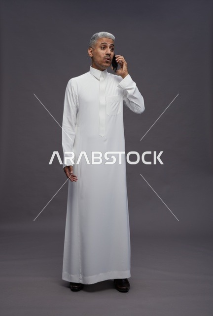 رجل سعودي بالثوب الأبيض يتحدث عبر الهاتف الجوال