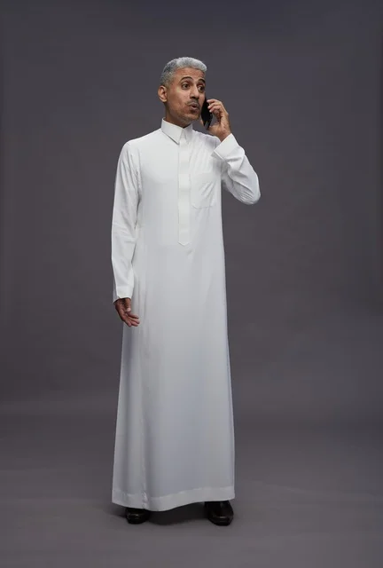 رجل سعودي بالثوب الأبيض يتحدث عبر الهاتف الجوال