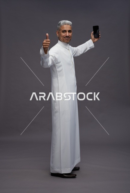 رجل سعودي مع هاتف ذكي وعلامة الإعجاب