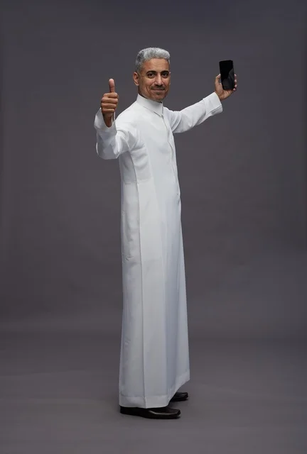 رجل سعودي مع هاتف ذكي وعلامة الإعجاب