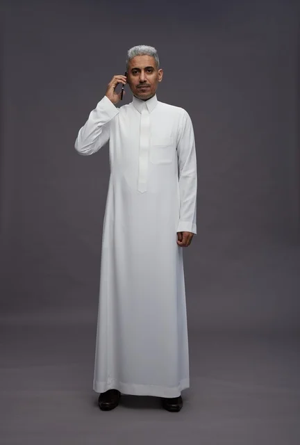 رجل سعودي بالثوب الأبيض يتحدث بالجوال في الاستوديو