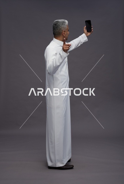 رجل سعودي بالثوب التقليدي يلتقط صورة سيلفي