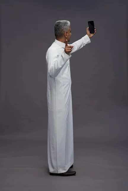 رجل سعودي بالثوب التقليدي يلتقط صورة سيلفي