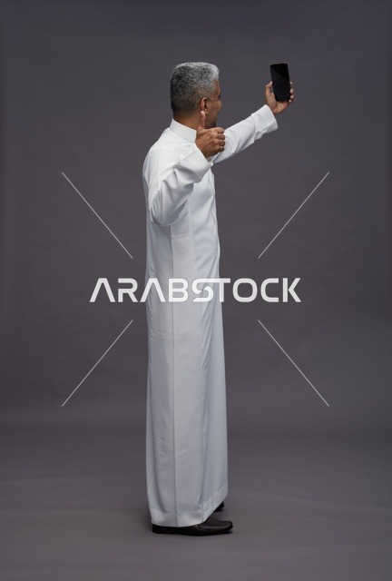 Saudi Man in White Thobe Taking Selfie with Smartphone
