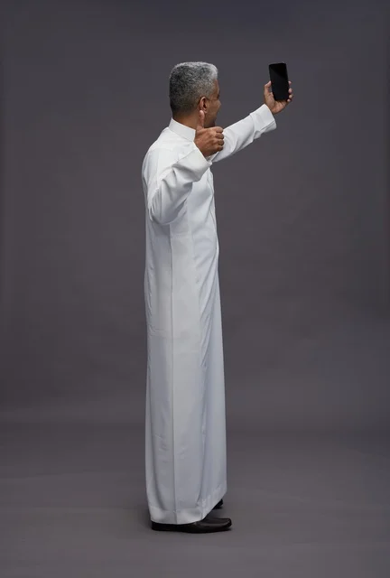 رجل سعودي بالثوب التقليدي يلتقط صورة سيلفي بالجوال