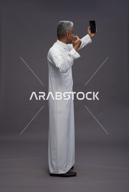 رجل سعودي بالزي التقليدي يلتقط سيلفي بالهاتف