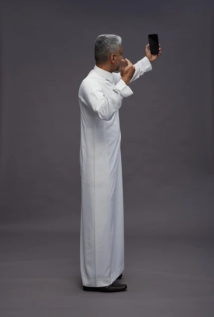 رجل سعودي بالزي التقليدي يلتقط سيلفي بالهاتف