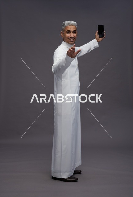 رجل سعودي بالثوب التقليدي يلتقط سيلفي في الاستوديو