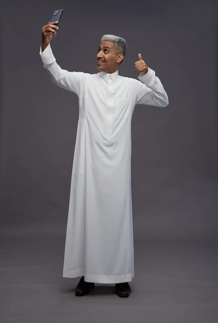 Saudi Man in Thobe Taking Selfie in Studio Thumbs Up