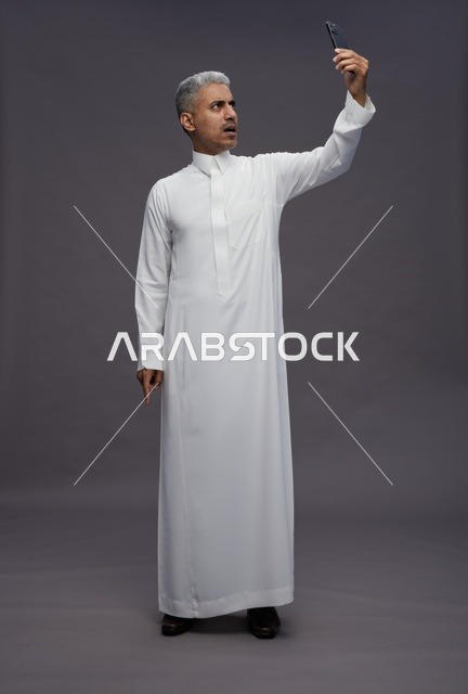 رجل سعودي بالثوب الأبيض يلتقط سيلفي في الاستوديو