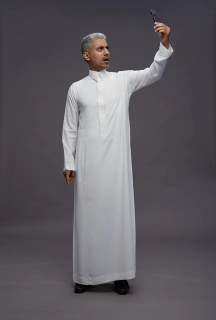 رجل سعودي بالثوب الأبيض يلتقط سيلفي في الاستوديو