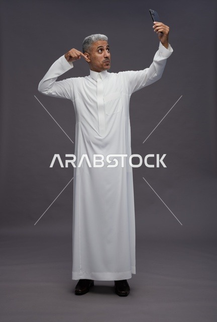 رجل سعودي بالزي التقليدي يلتقط صورة سيلفي