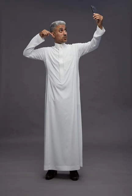 رجل سعودي بالزي التقليدي يلتقط صورة سيلفي