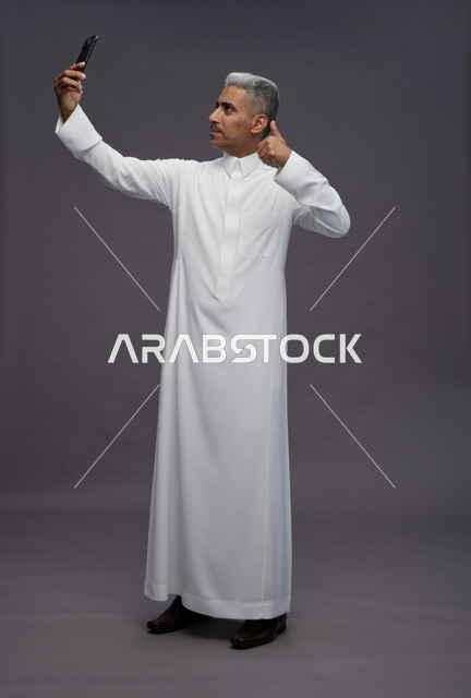 رجل سعودي بالثوب يلتقط سيلفي مع علامة إعجاب