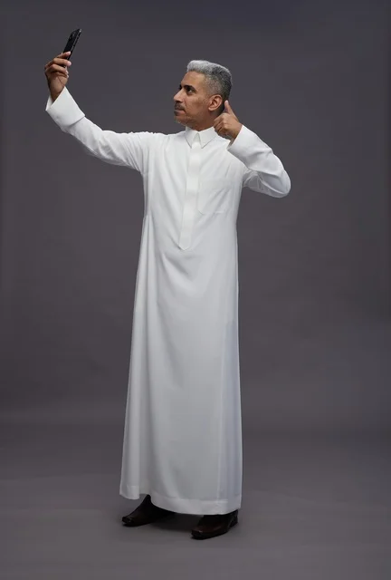 رجل سعودي بالثوب يلتقط سيلفي مع علامة إعجاب
