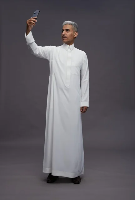 رجل سعودي بالثوب التقليدي يلتقط سيلفي في الاستوديو
