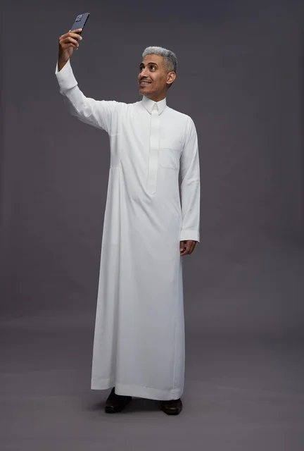 رجل سعودي بالثوب التقليدي يلتقط صورة سيلفي بالجوال