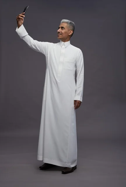 رجل سعودي بالثوب الأبيض التقليدي يلتقط صورة سيلفي