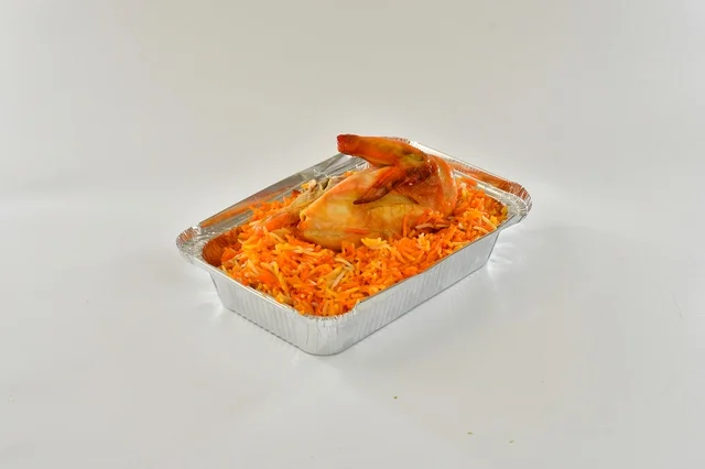 A plate of Saudi red mandi rice with roasted chicken, popular orange-colored rice, traditional Saudi popular restaurant, white background.