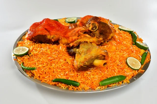 A plate of Saudi red mandi rice with roasted chicken, popular orange-colored rice, traditional Saudi popular restaurant, white background.