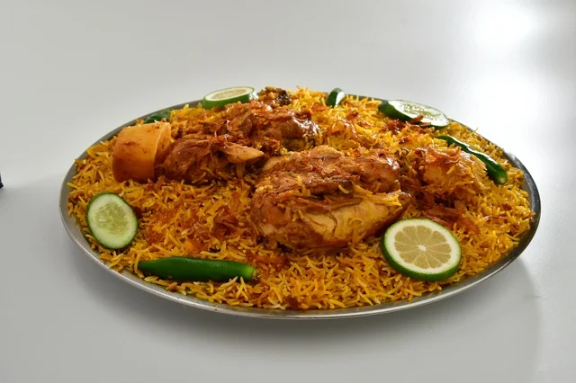 طبق من الرز المندي الاحمر السعودي مع الدجاج المحمر , أرز شعبي باللون البرتقالي , مطعم سعودي شعبي تقليدي, خلفيه بيضاء