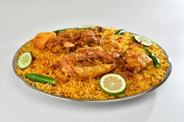 طبق من الرز المندي الاحمر السعودي مع الدجاج المحمر , أرز شعبي باللون البرتقالي , مطعم سعودي شعبي تقليدي, خلفيه بيضاء