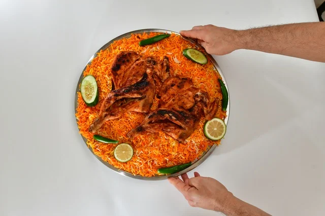 A plate of Saudi mandi rice with roasted chicken, red popular rice, traditional Saudi popular restaurant, white background.
