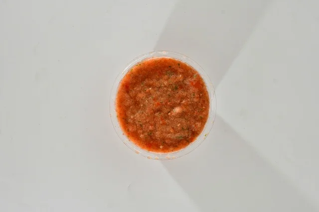 A vertical upper image of hot tomato sauce, traditional Saudi sauce, red salad with red pepper, popular Saudi appetizers, white background.