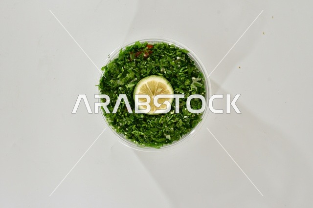 صوره علويه عاموديه لطبق من التبوله الخضراء , سلطة صحيه بالبقدونس , مطعم سعودي شعبي تقليدي, خلفيه بيضاء