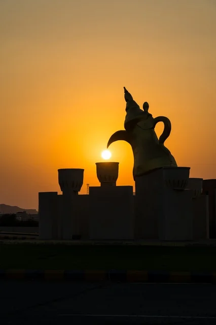 The view of the sunset at the Arabic coffee roundabout with coffee cups in the village of Mudrikah on the road to Jeddah in Mecca, a historic popular area, with mountainous terrain and paved roads in the city, Kingdom of Saudi Arabia.