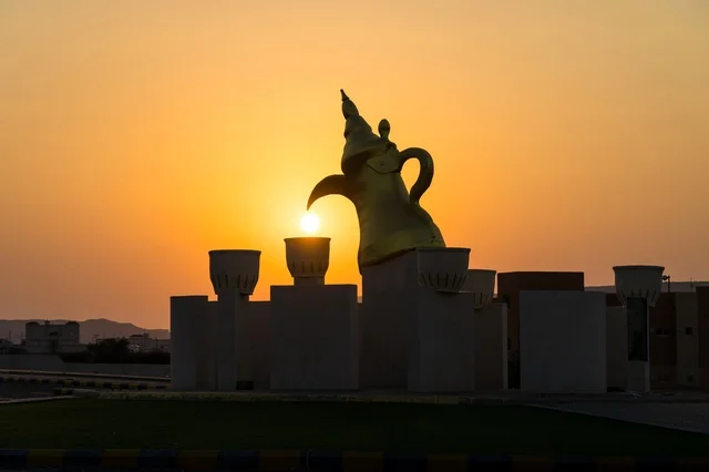 The view of the sunset at the Arabic coffee roundabout with coffee cups in the village of Mudrikah on the road to Jeddah in Mecca, a historic popular area, with mountainous terrain and paved roads in the city, Kingdom of Saudi Arabia.
