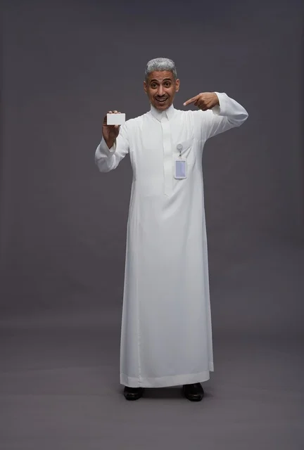 بورتريه لرجل عربي سعودي خليجي يرتدي الثوب الابيض يعرض بطاقة ائتمان بيضاء فارغه ويشير اليها, كرت تعريفي شخصي, الجسم بالكامل, خلفيه رماديه