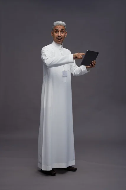بورتريه لرجل عربي سعودي خليجي يرتدي الثوب الابيض يحمل بيده جهاز التابليت المحمول, ايماءات وتعابير مختلفه, كامل الجسم, خلفيه رماديه