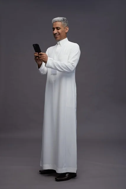 A portrait of an Arab Saudi Gulf man wearing a white thobe using a mobile phone, with various gestures and expressions, full body, gray background.
