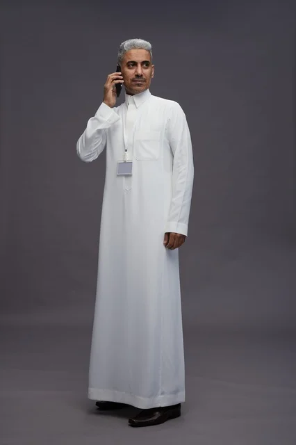 A portrait of an Arab Saudi Gulf man wearing a white thobe using a mobile phone, with various gestures and expressions, full body, gray background.