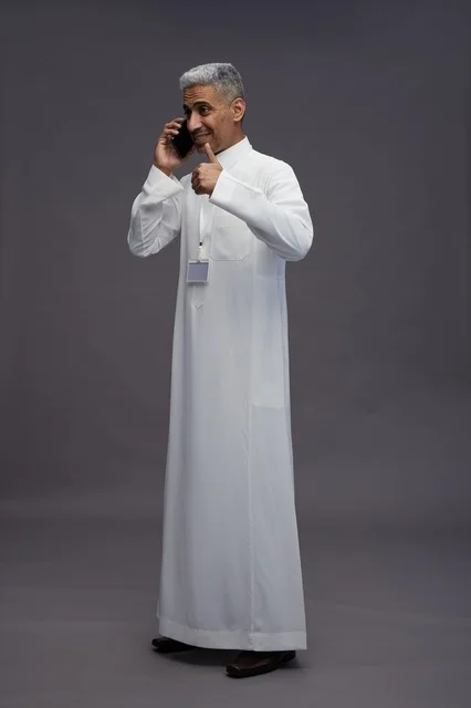 A portrait of an Arab Saudi Gulf man wearing a white thobe using a mobile phone, with various gestures and expressions, full body, gray background.