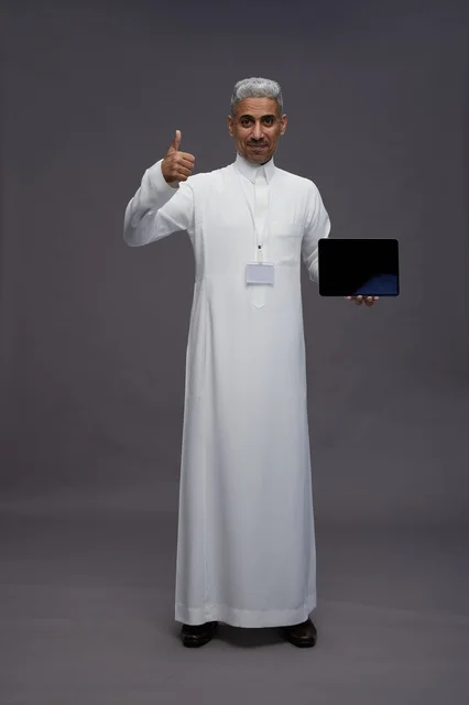 رجل سعودي يعرض جهازًا لوحيًا بشاشة فارغة
