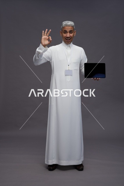 رجل سعودي يعرض جهازًا لوحيًا بشاشة فارغة