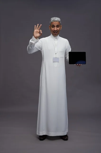 رجل سعودي يعرض جهازًا لوحيًا بشاشة فارغة