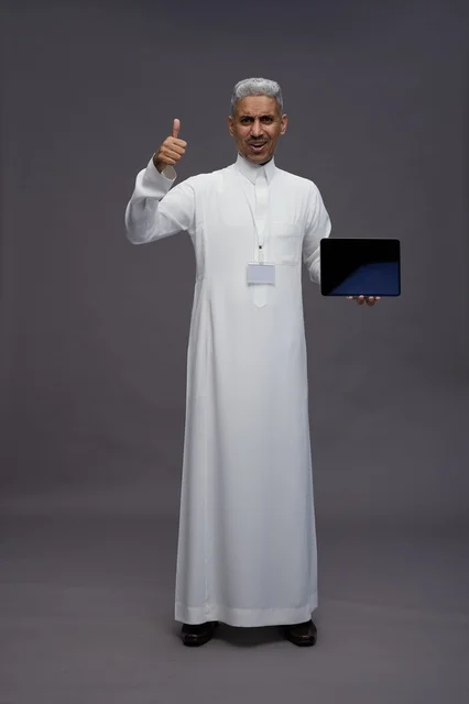 رجل سعودي يعرض جهازًا لوحيًا بشاشة فارغة