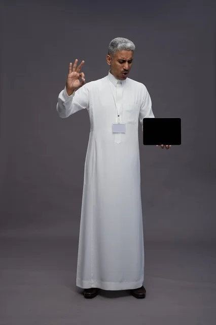 رجل سعودي يعرض جهازًا لوحيًا بشاشة فارغة