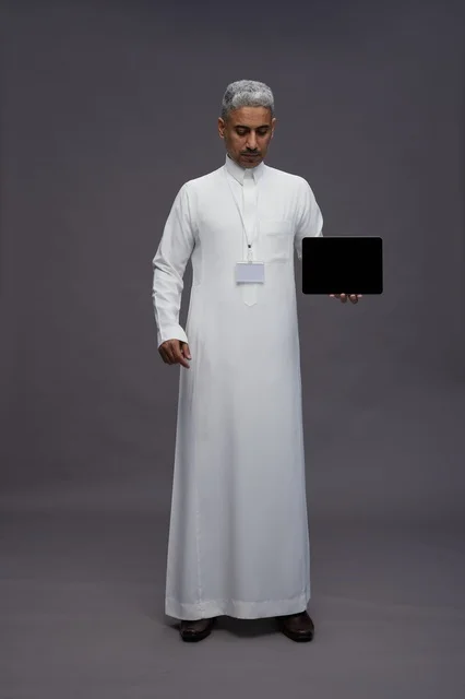 رجل سعودي يعرض جهازًا لوحيًا بشاشة فارغة