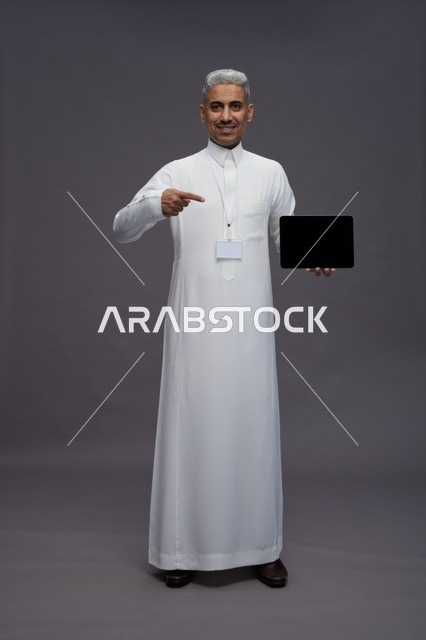 رجل سعودي يعرض جهازًا لوحيًا بشاشة فارغة