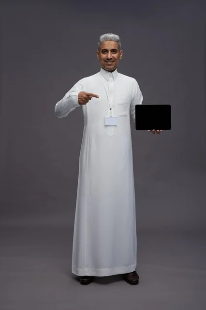 رجل سعودي يعرض جهازًا لوحيًا بشاشة فارغة